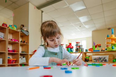 Anaokulunda ya da çocuk yuvasında farklı duyguları olan kartları düşünen küçük bir kız. Seçici odak.