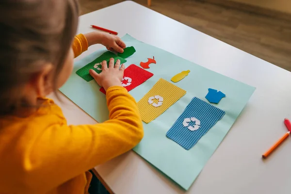 Little girl playing with poster of garbage containers for sorting at kindergarten — Stockfoto