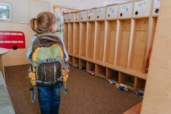 First day at school or kindergarten. Back view of little girl with backpack going inside the school. Back to school concept.