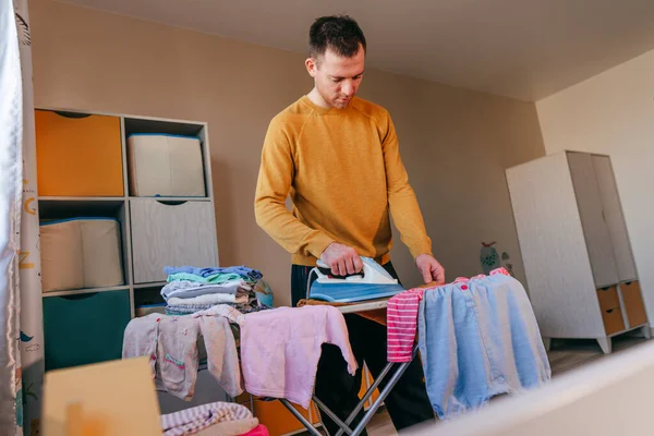 Young Man Ironing Baby Clothes Children Room Father Doing Chores — Stock Fotó