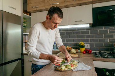 Pişirme kabına balık koyan adam aşçı için çipura ve sebze hazırlıyor. Seçici odak.