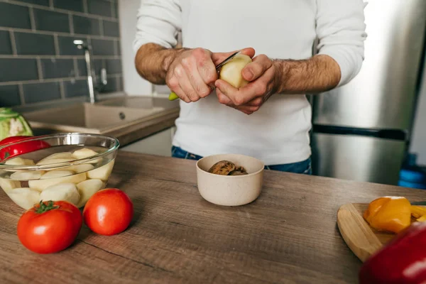 Patates soyan adam. Mutfakta sebze pişiren tanınmamış bir adam. Erkeklerin ellerini kapat ve patatesi aşçıya hazırla. Seçici odak.
