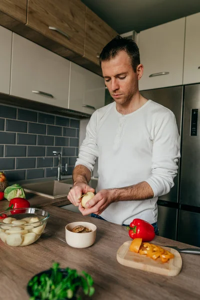 Man peeling potatoes. Young man cooking vegetables in the kitchen preparing potato. Selective focus.