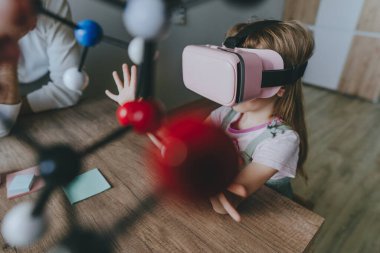 Küçük kız moleküler yapıyı öğrenmek için sanal gerçeklik gözlüğü kullanıyor. Modern eğitim bilim konsepti. Seçici odak.