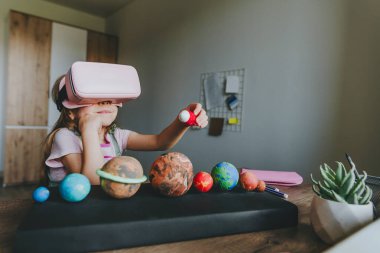 Güneş sistemi gezegenlerini öğrenmek için evde sanal gerçeklik gözlüğü kullanan küçük bir kız. Modern eğitim bilim konsepti. Seçici odak.