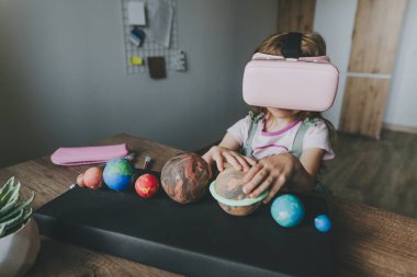 Güneş sistemi gezegenlerini öğrenmek için evde sanal gerçeklik gözlüğü kullanan küçük bir kız. Modern eğitim bilim konsepti. Seçici odak.