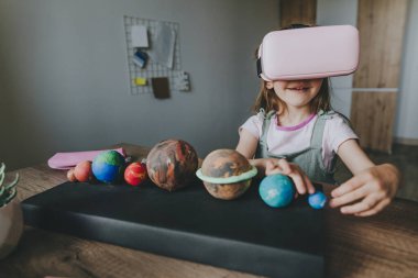 Güneş sistemi gezegenlerini öğrenmek için evde sanal gerçeklik gözlüğü kullanan küçük bir kız. Modern eğitim bilim konsepti. Seçici odak.