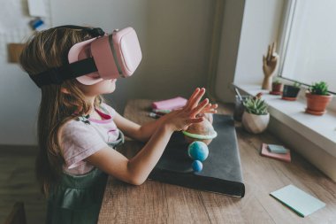 Güneş sistemi gezegenlerini öğrenmek için evde sanal gerçeklik gözlüğü kullanan küçük bir kız. Modern eğitim bilim konsepti. Seçici odak.