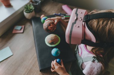 Güneş sistemi gezegenlerini öğrenmek için evde sanal gerçeklik gözlüğü kullanan küçük bir kız. Modern eğitim bilim konsepti. Seçici odak.