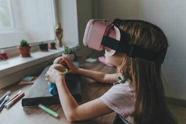 Güneş sistemi gezegenlerini öğrenmek için evde sanal gerçeklik gözlüğü kullanan küçük bir kız. Modern eğitim bilim konsepti. Seçici odak.