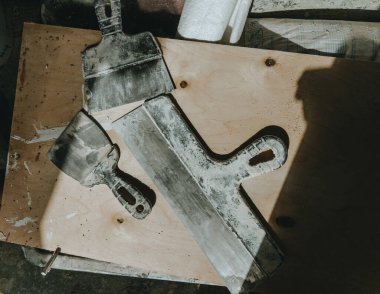 Ahşap zemine güneş ışığı ve gölgelerle sıva yapmak için farklı boyutlarda inşaat malaları. Üst manzara, düz uzanma.