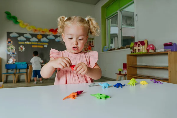 Maluch Dziewczyna Bawi Się Kolorowe Dinozaury Zabawki Przedszkolu — Zdjęcie stockowe