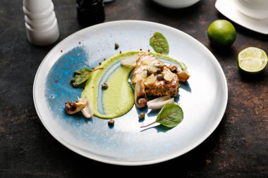 Fıstıklı ızgara ton balığı bifteği, kapari ve bezelye. Mavi tabakta lezzetli bir yemek. Yemek fotografı. Şef servis yapıyor..