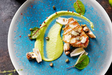 Fıstıklı ızgara ton balığı bifteği, kapari ve bezelye. Mavi tabakta lezzetli bir yemek. Yemek fotografı. Şef servis yapıyor..