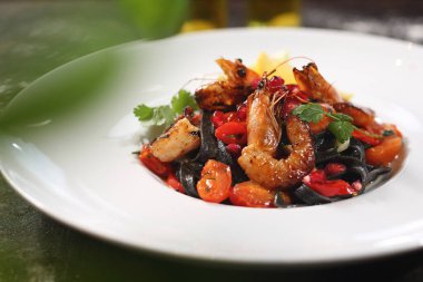 Deniz mahsullü siyah tagliatelle makarna. Deniz mahsullü makarna. Tabakta iştah açıcı yemek, mutfak fotoğrafçılığı. Gıda arkaplanı.