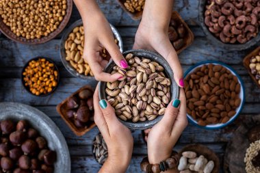 İki kadının elinde bir kase şam fıstığı ve arka planda da çeşitli fındıklar. Fındık çeşitliliği.