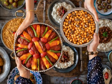 Aile üyelerinin elinde birçok çeşit yiyecek var. etli nohut ve bulgur pilavi adında yerel yiyecekler. Havan topu konsepti. Yerel ev yapımı gıdaların çeşitliliği.   