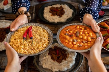 Aile üyelerinin elinde birçok çeşit yiyecek var. etli nohut ve bulgur pilavi adlı yerel gıda