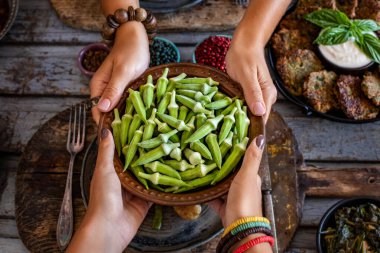 Bakır kasedeki bamya iki kadının elinde. Bamya 