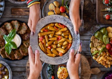 Okra in the copper bowl at the hands of two women. Sira gecesi