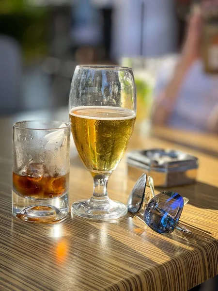 Uma Mesa Copo Uísque Copo Cerveja Óculos Sol Azuis — Fotografia de Stock