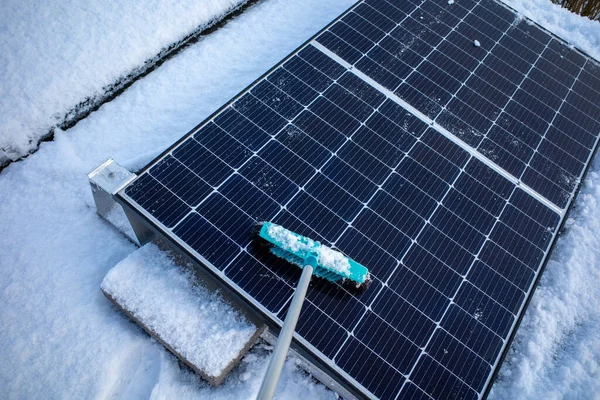  Çatıdaki fotovoltaik sistemin güneş panelleri süpürgeyle kardan temizleniyor.