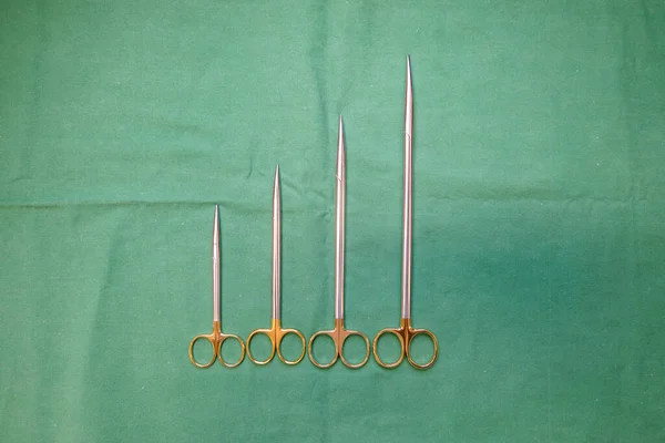 Nożyczki Chirurgiczne Różnej Wielkości Leżą Obok Siebie Zielonej Podstawie — Zdjęcie stockowe