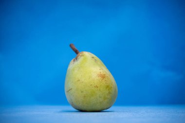 Bir armudun yakın çekimi duruyor ve arkaplan mavi.