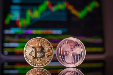 Grafik grafiğinin önünde bir dalgalı paranın yanında bir bitcoin.