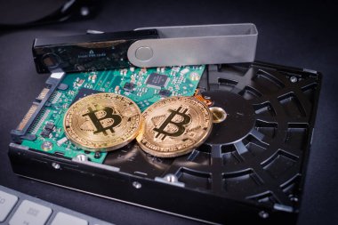 İki bitcoin madeni para bir sabit diskin içinde donanım cüzdanı ve klavyenin yanında. 