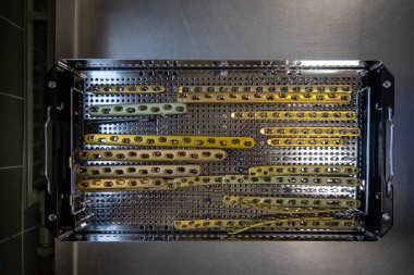 Femoral çatlakların tedavisi için altın renkli titanyum levhalar bir alet tepsisinde saklanır.