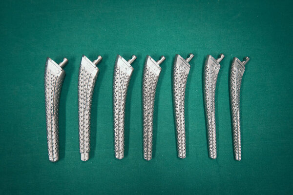 some Surgical rasps of different sizes for a transfemoral prosthesis lie on a green surgical drape