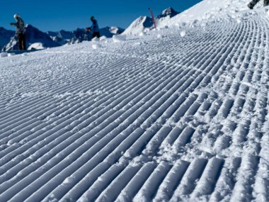 Taze bakımlı kar yamacına yakın ve gökyüzü bulutsuz ve mavi.