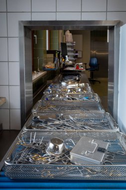 Bir hastanenin sterilizasyon bölümünde, temizlenmiş cerrahi aletler taşıyıcı bandın üzerinde duruyor.