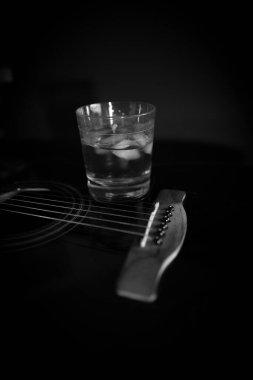 Gitarın üzerinde siyah beyaz buzlu bir bardak viski var.