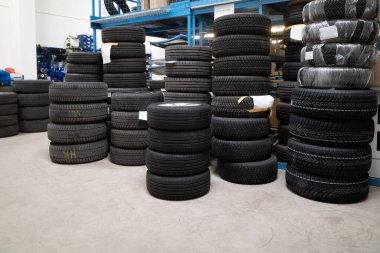 in the warehouse of a car repair shop are several stacks of summer wheels