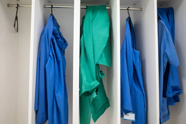 green and blue surgical gowns hang in an operating room in a hospital
