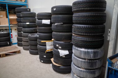 Bir araba tamirhanesinin deposunda tekerlek değiştirmeye hazır bir sürü yaz lastiği var.