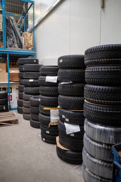 in the depot of a car repair shop there are many summer tires ready for a wheel change