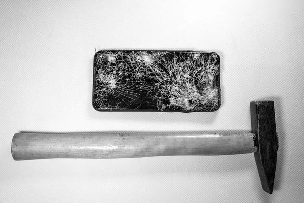 在被完全摧毁的手机旁边躺着一把锤子 — 图库照片