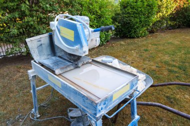 Taşlar için dairesel bir testerenin yanında taş kırıntılarıyla dolu bir el arabası var.