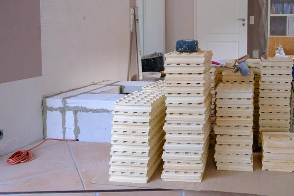 a pile of tiles for the construction of a tile stove stand next to a foundation