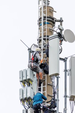 two Telekom technicians perform work on a transmission tower