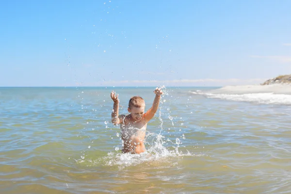 Kind jongen hagelslag water in een zee — Stockfoto