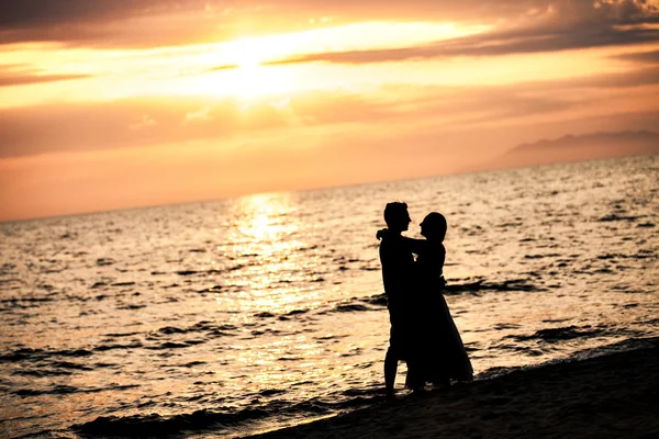 Amantes Besándose en la playa al atardecer — Foto de Stock