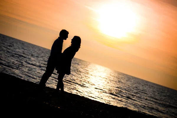 Szerelmeseinek csók a tengerparton naplementekor — Stock Fotó