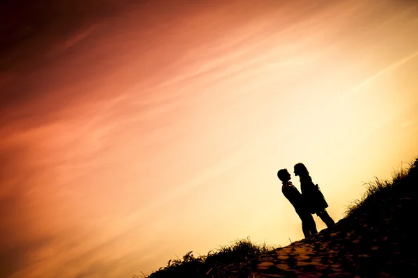 Коханці цілуються на пляжі на заході сонця — стокове фото