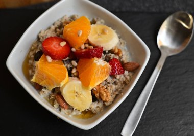 Siyah ahşap arka planda beyaz kasede chia tohumları olan meyve salatası. Üst Manzara. Yakın çekim..