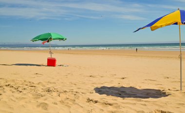 Rüzgarsız ve güneşli bir yaz gününde temiz kumu ve turkuaz suyu olan mükemmel bir sahilde tek yeşil şemsiye. Tropik arkaplan, kopyalama alanı, üst görünüm