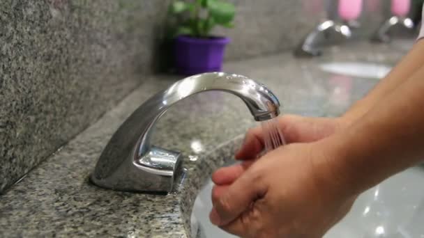 Человек моет руки с помощью автоматического крана в общественном туалете — стоковое видео